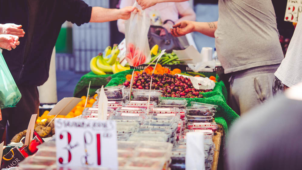 A man buys fruit from a fruit and vegetable stand